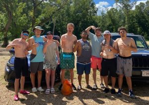 Putting up a "4" sign with their hands as they prepare for a float trip in a local river.